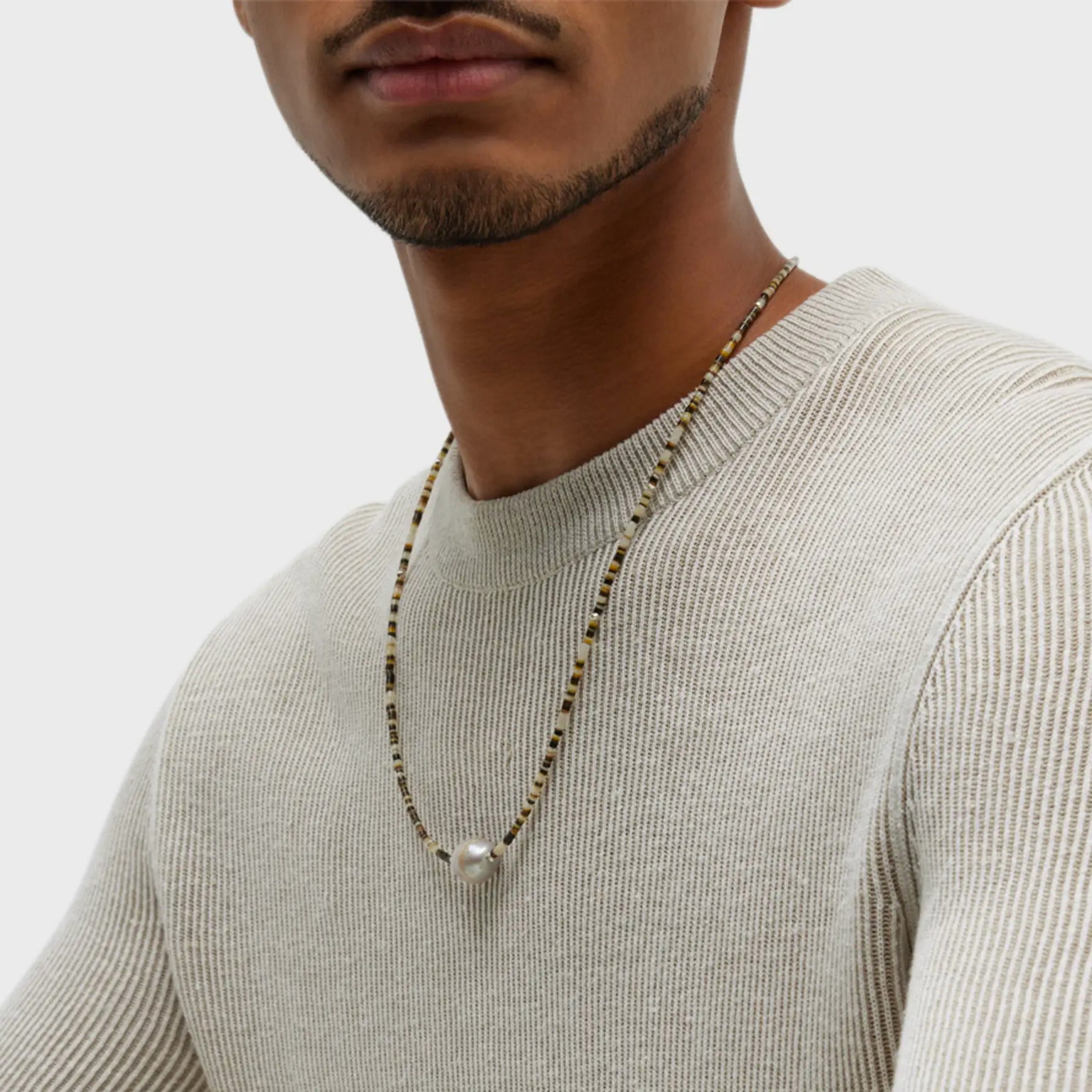 Male model wearing the Shell Beaded Necklace with Freshwater Pearl Center and Sterling Silver Accents.