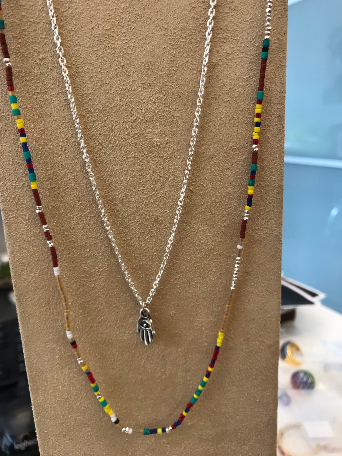 Layered multicolor seed bead necklace with silver Hamsa charm styled on display bust, Jan Leslie