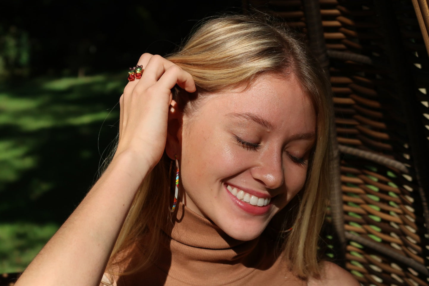 Close up photo of model wearing Jan Leslie's Stripe Enamel & Gemstone Sterling Silver 55mm Hoop Earrings in rainbow on gold.