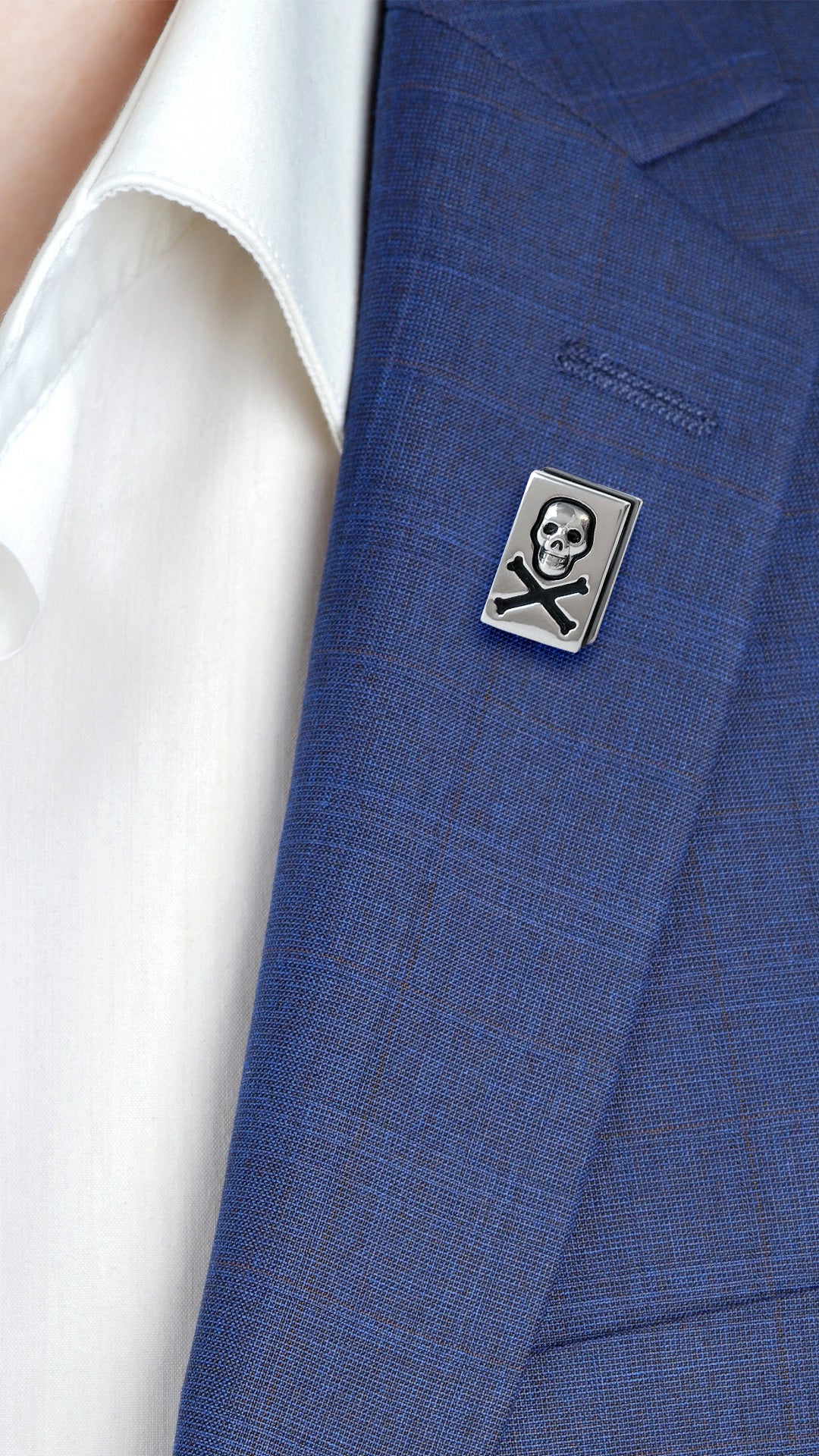 Male model wearing the Skull and Crossbones Sterling Silver Lapel Pin on a blue suit jacket lapel.