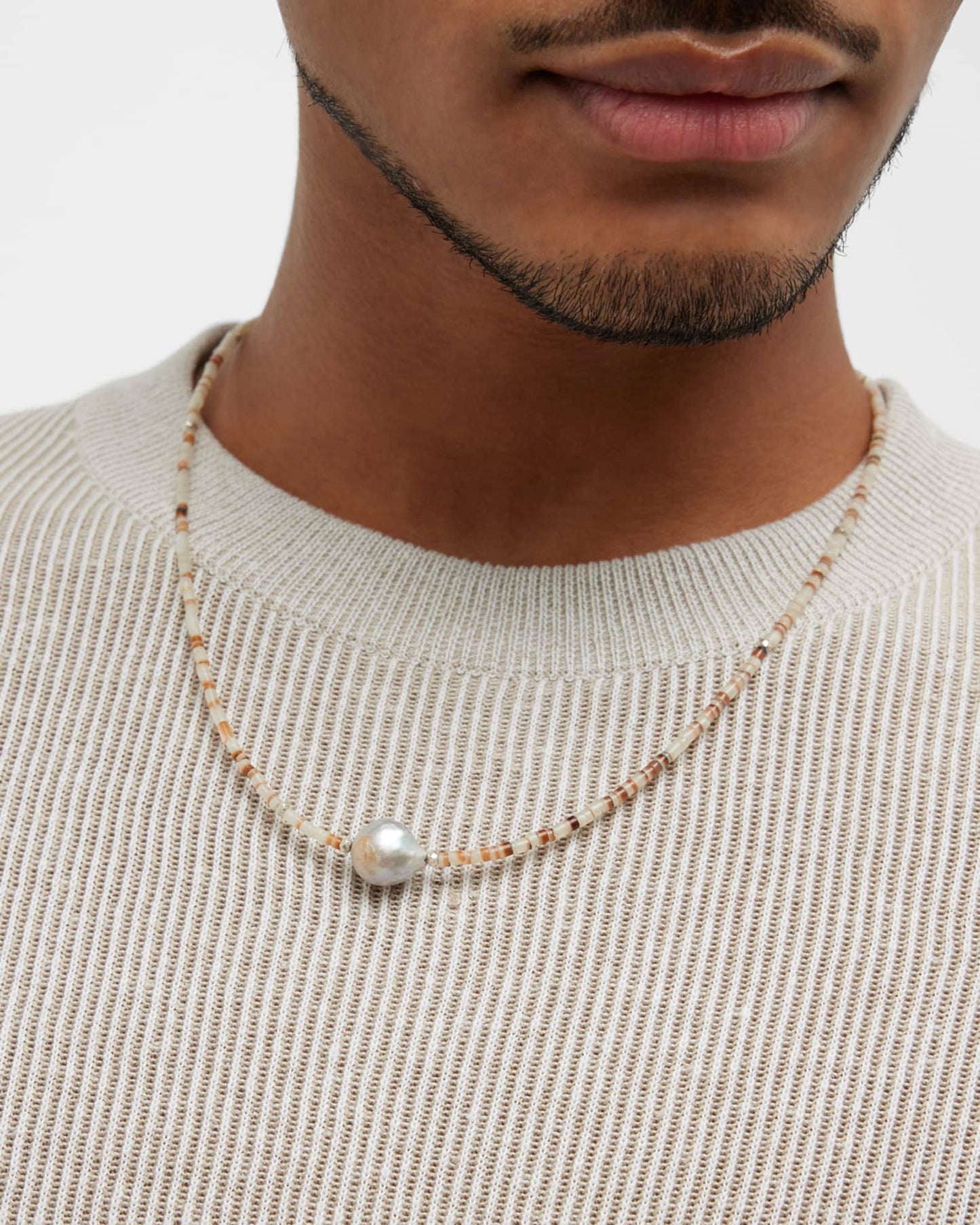 Close up of male models neck donning the Freshwater Pearl Center White Shell Beaded Necklace with Sterling Silver Accents.