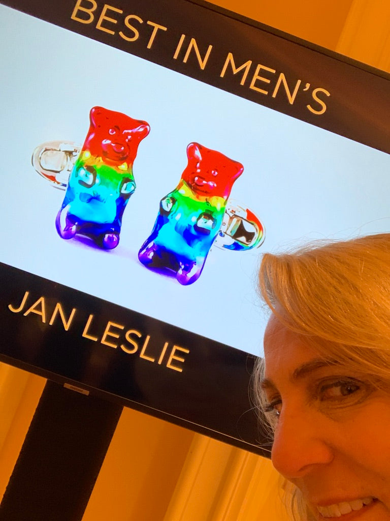 Jan Leslie in front of a digital display showcasing her AWARD WINNING Rainbow Enamel Gummy Bear Sterling Silver Cufflinks for the "Best In Men's" category at the Couture Design Awards in Las Vegas, NV.