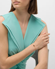 Woman in teal dress wearing rose gold vermeil red tiger eye heart chain bracelet at wrist showing burgundy-red tiger eye heart station on rose gold cable chain by Jan Leslie