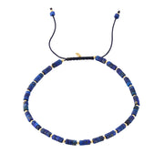 Lapis lazuli heishi cylinder bead bracelet with gold vermeil rondelle spacers top-down view showing full bead strand black macramé cord and Jan Leslie gold tag charm by Jan Leslie