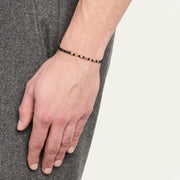 Man wearing black onyx beaded bracelet with gold and diamond accents on wrist.