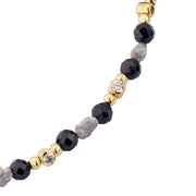 Close-up of black onyx and rough diamond beads with gold bezel-set diamond accents on luxury bracelet.