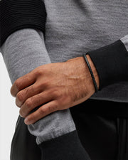 Black braided leather bracelet with magnetic clasp worn on man's wrist 