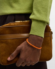 Orange braided leather bracelet with magnetic clasp worn on man's wrist 
