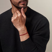 Red braided leather bracelet with magnetic clasp worn on man's wrist with black sweater