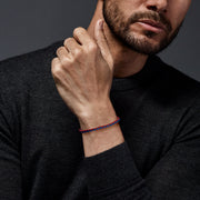 Red and blue two-tone braided leather bracelet with magnetic clasp worn on man's wrist with dark grey sweater