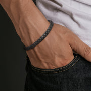 Man wearing double-strand black braided leather bracelet on wrist.
