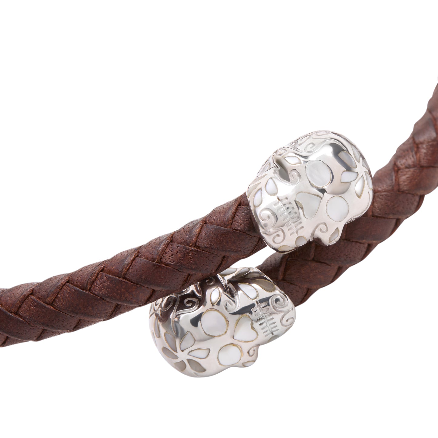 Close-up of the sterling silver sugar skull end caps on the brown braided leather bracelet intricately engraved with floral scrollwork and mother-of-pearl inlay.
