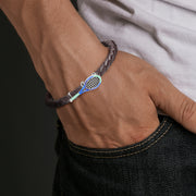 brown braided leather tennis racket charm bracelet on wrist.