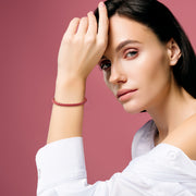  Model wearing sunset red braided leather bracelet with gold magnetic clasp on wrist with white top by Jan Leslie.