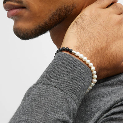Male model wearing the Men's Freshwater Pearl and Black Onyx Gemstone Split Beaded Bracelet. 