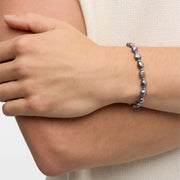 Iridescent gray freshwater baroque pearl bracelet with gold accent beads on wrist.