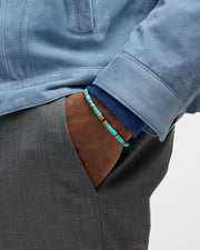 Men's turquoise heishi bead bracelet with brass spacers styled with blue suede jacket and grey trousers, Jan Leslie