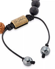 Close-up of engraved Jan Leslie antique brass barrel clasp with hematite end beads on adjustable black cord bracelet