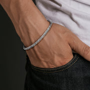 Man wearing sterling silver twisted rope bracelet with hand in jeans pocket.