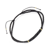 Double-strand matte black heishi bead bracelet with gold accent beads and black stone bar full silhouette showing adjustable cord and bead detail by Jan Leslie
