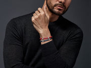 Man in dark grey turtleneck stacking red and navy rubber steel cable ID bracelets — Jan Leslie