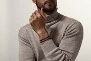 Man in beige turtleneck stacking navy and brown braided leather bracelets — Jan Leslie