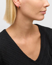 Model in black V-neck sweater wearing navy and red stripe enamel gold mini hoop earring — Jan Leslie