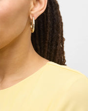 Model in yellow top wearing small gold hoop earrings with multicolor enamel tile inlays — Jan Leslie