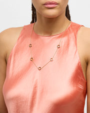 Model in coral halter dress wearing multicolor enamel five-circle station gold necklace — Jan Leslie