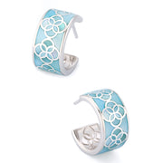 Angled staggered pair of sterling silver wide-band turquoise blue enamel floral lattice open C-hoop earrings showing sky blue enamel inlay with silver quatrefoil overlay pattern, engraved silver interior floral detail, and post pin closure, Jan Leslie 