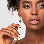 Woman wearing 18K gold vermeil deep royal blue petal Seed of Life drop earrings close-up showing mini huggie leverback wire and quatrefoil clover pendant with Seed of Life gold lattice over vivid deep royal blue stone by Jan Leslie