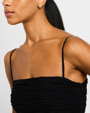 Woman in black dress wearing 18K gold vermeil white mother-of-pearl petal Seed of Life stud earring at lobe three-quarter rear view showing white MOP clover face and gold comfort back disc by Jan Leslie
