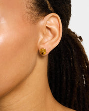 Woman wearing solid gold quatrefoil clover stud earrings with high-polish domed finish, luxury minimalist women's fine jewelry lifestyle.