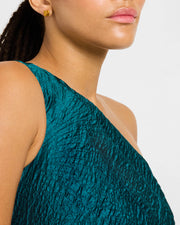 Woman in teal metallic dress wearing 18K gold vermeil sculptural petal clover stud earring at lobe showing raised convex domed polished gold clover face by Jan Leslie