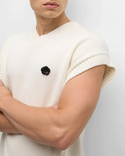 Model wearing matte black sculpted flower lapel pin with crystal center on cream knit sweater vest full torso view by Jan Leslie