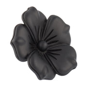 Matte black sculpted five-petal flower lapel pin with matte bud center showing engraved petal veining and full silhouette by Jan Leslie.
