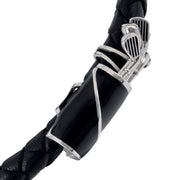 Close-up of black double-strand braided leather bypass bracelet showing two pavé crystal golf ball end caps