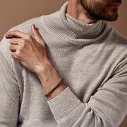 Brown braided leather bracelet with a silver clasp worn on man's wrist