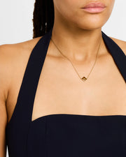 Model in black halter dress wearing tiger's eye quatrefoil gold pendant necklace — Jan Leslie