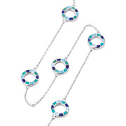 Close-up of five open circle pendants with segmented navy, teal, and sky blue enamel mosaic detail on sterling silver cable chain.