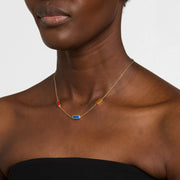 Woman in black strapless top wearing a gold cable chain station necklace with mixed carnelian, lapis lazuli, and tiger's eye rectangular gemstone pendants.