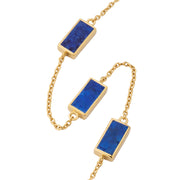 Close-up of three rectangular lapis lazuli stones with gold pyrite flecks in polished gold bezel settings on cable chain.