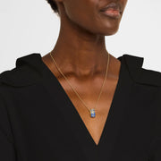 Woman wearing 18K gold vermeil lapis lazuli petal Seed of Life barrel pendant necklace at collarbone with black V-neck dress showing deep royal blue lapis ground and gold Seed of Life cutwork lattice by Jan Leslie