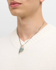 Man wearing oxidized sterling silver box chain necklace with malachite leaf abalone surfboard and feather charm cluster at collarbone with cream ribbed V-neck sweater by Jan Leslie