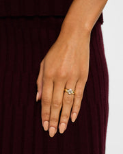 Woman's hand wearing gold vermeil sterling silver slim band white mother of pearl floral lattice quatrefoil ring on middle finger against burgundy pleated knit skirt, Jan Leslie 