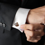 Man fastening sterling silver brown enamel monkey cufflinks on white French cuff with black tuxedo jacket, luxury novelty men's fine jewelry lifestyle.