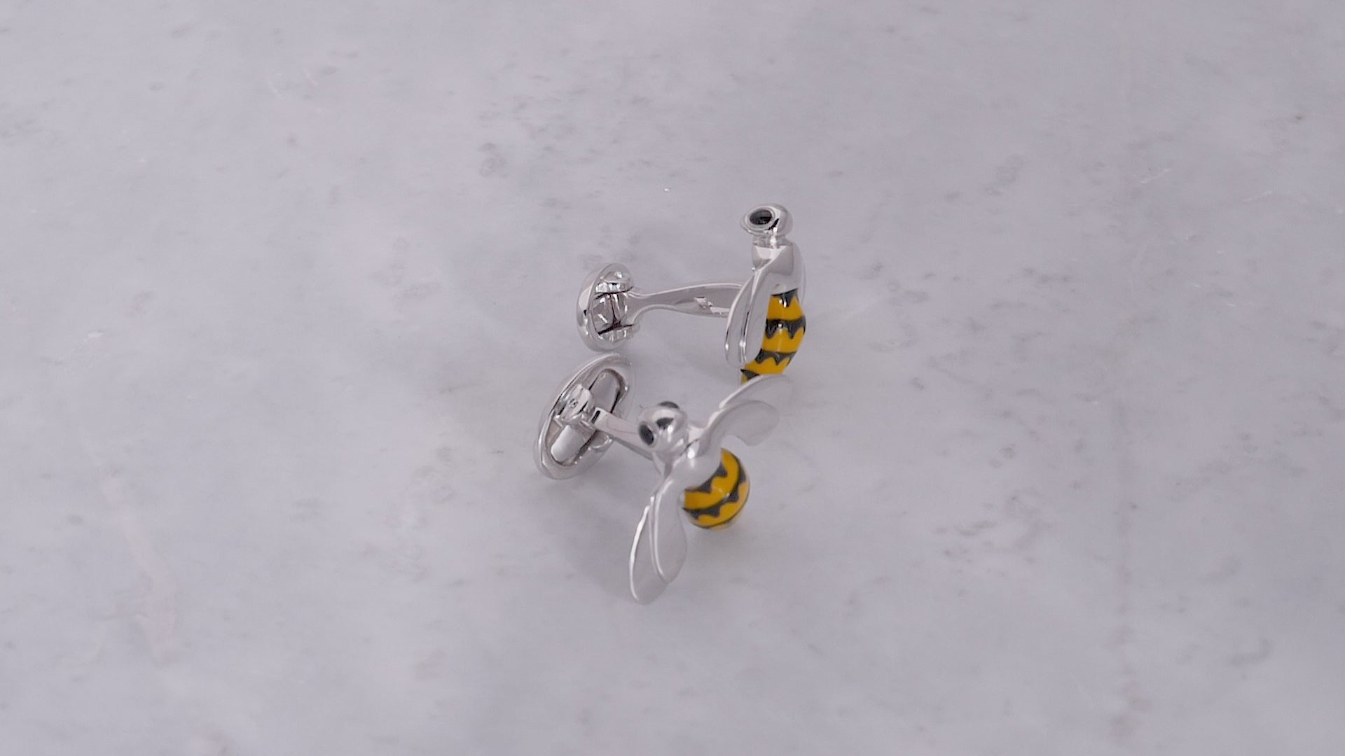 180 video of the Triumphant Bee Sterling Silver Cufflinks on a grey marbled background. 