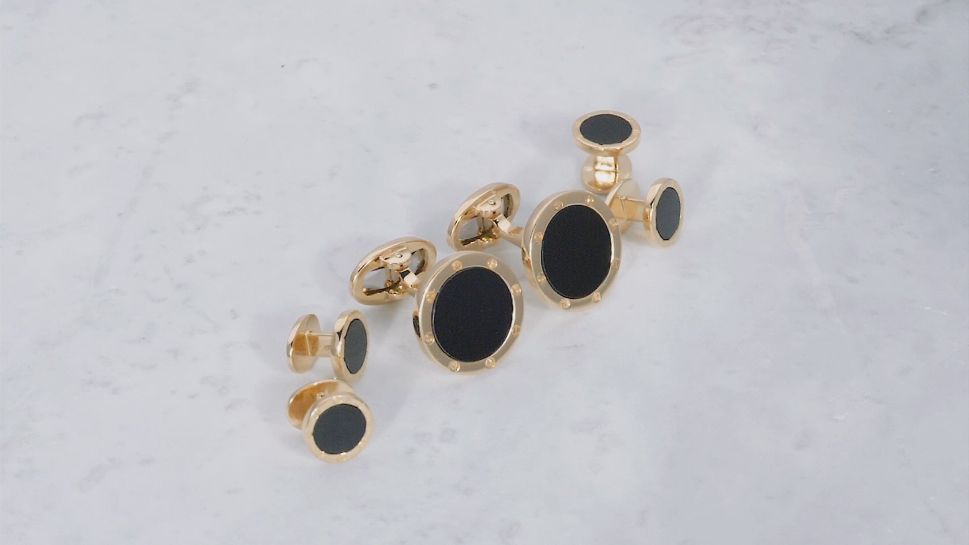 180 view of the Onyx Gemstone with Rivet Etch Details 18K Yellow Gold Cufflinks & Tuxedo Studs Set on a marble background. 