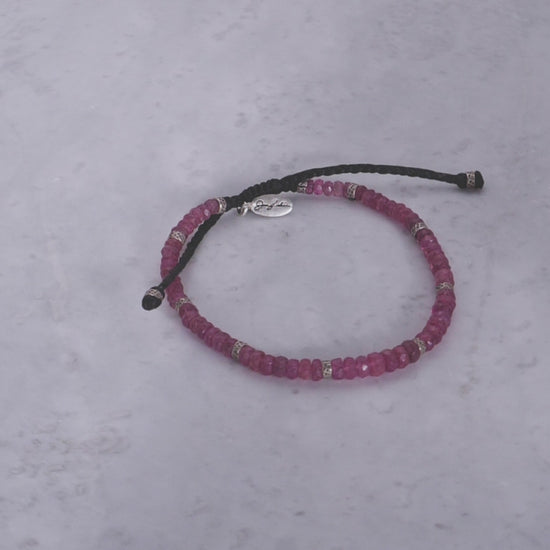 360 video of the an Leslie Faceted Ruby Gemstone Bracelet with Black Pull Cord on marble background. 