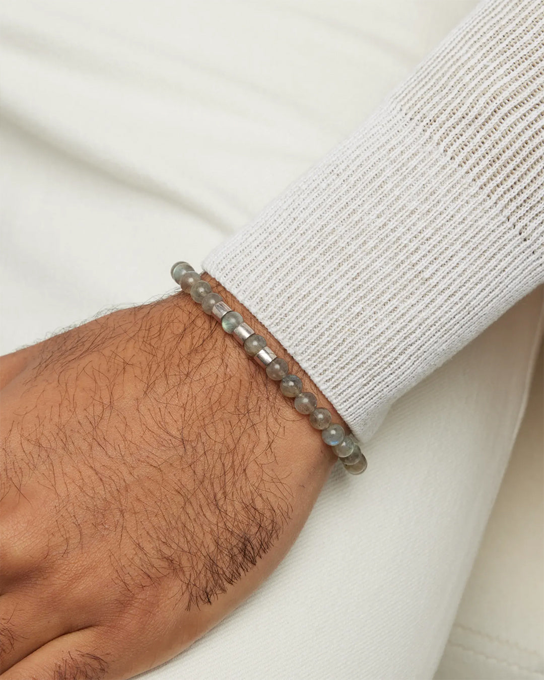 Close up of male models wrist wearing the Gemstone Beads and Sterling Silver Spacer Elastic Bracelet in labradorite. 